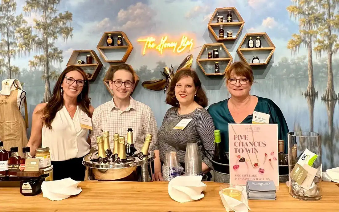 Symmetry Jewelers team at in-store event with champagne and jewelry display.