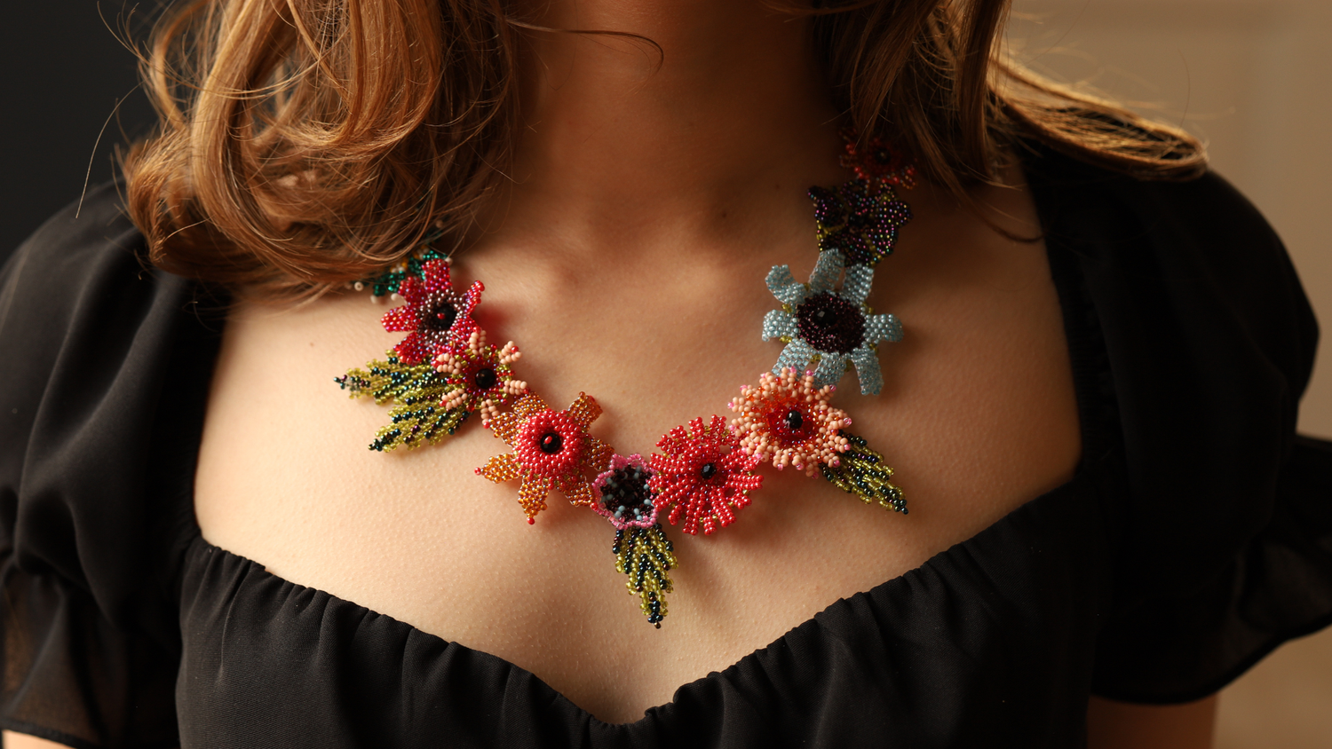 Handcrafted floral beaded statement necklace worn on black dress – artisan fine jewelry.